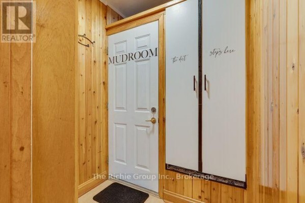 Mudroom entrance with white door, storage cabinets, and wood paneling - 624 Cedar Street W Shelburne