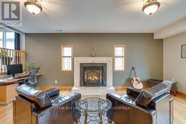 Living room with gas fireplace, leather chairs, desk, and guitar - 624 Cedar Street W Shelburne