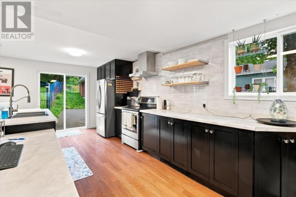 Modern kitchen with dark cabinets, stainless steel appliances, and a window overlooking the yard. - 624 Empire Avenue, St  John S