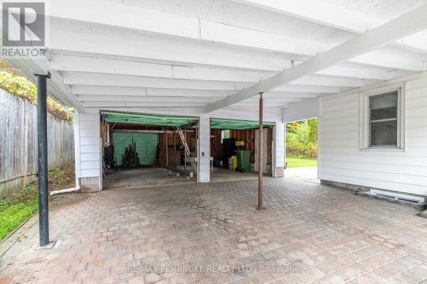 View under the carport showing two green garage doors and storage on the right. - 624 Hamilton Street W, Laurentian Valley