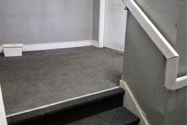Carpeted staircase with gray walls and white handrail leading to a doorway. - 624 King Street E Unit# 101, Cambridge
