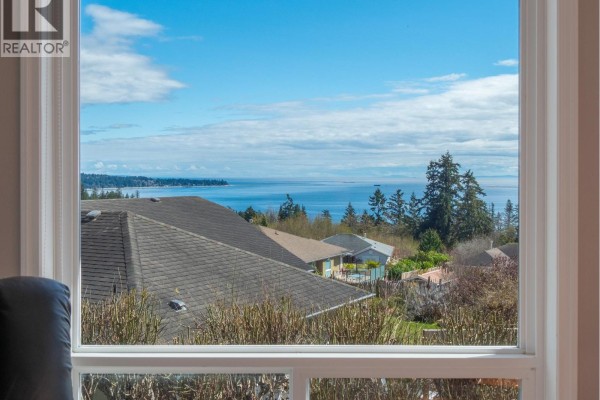 View of the ocean and coastline through a large living room window. - 6249 Baillie Road, Sechelt
