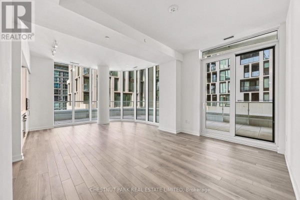 Spacious living area with light wood floors, floor-to-ceiling windows, and balcony access. - 625 - 230 Simcoe Street, Toronto