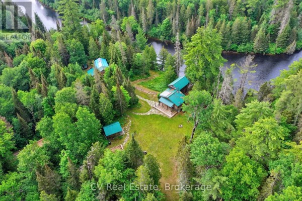 Exterior of a rustic wooden outbuilding with a covered open storage area and a large garage door. - 625 Chetwynd Road, Armour