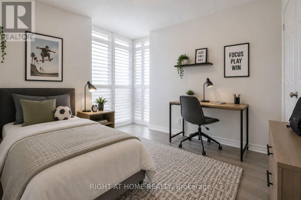 Bedroom with a bed, desk, chair, and white plantation shutters covering the windows. - 626 - 18 Mondeo Drive, Toronto