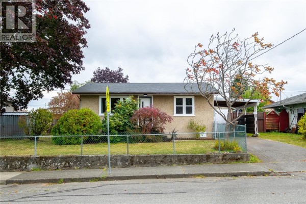 Front exterior of a small bungalow with a stucco finish and a well-maintained lawn. - 626 16th St, Courtenay