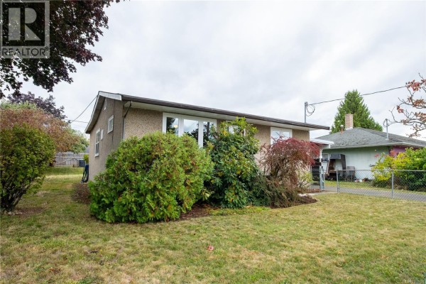Side exterior view of the house showing landscaping and neighboring properties. - 626 16th St, Courtenay