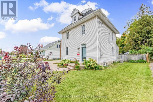 Side view of a white two-story house with a pitched roof, green lawn, and shrubs in the foreground. - 626 Hamilton Street W, Laurentian Valley