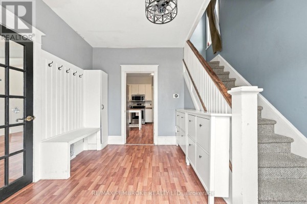 Interior entryway with hardwood floors, white bench and coat rack, shoe cabinets, and grey carpeted stairs. - 626 Hamilton Street W, Laurentian Valley