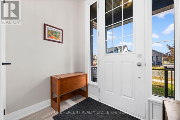 Interior view of the front entrance with a white door, large windows, and a wooden antique chest. - 626 Haylock Gardens, Peterborough