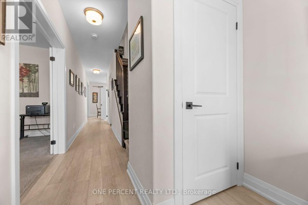 A long, bright hallway with light wood floors, white doors, and framed pictures on the walls. - 626 Haylock Gardens, Peterborough