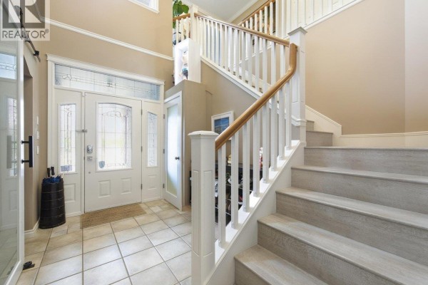 Interior foyer with tile flooring, a white staircase with wood banister, and double front doors. - 6260 Richards Drive, Richmond