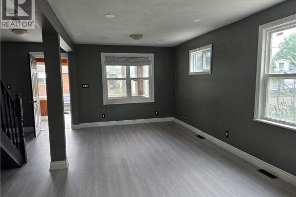 Modern kitchen with white cabinets, gray backsplash, and bar seating with two stools. - 6269 Franklin Avenue, Niagara Falls