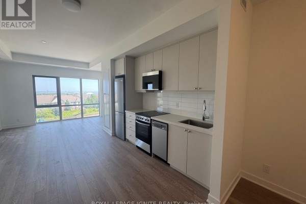 Modern open-concept kitchen with white cabinetry, stainless steel appliances, and hardwood floors. - 627 - 51 Clarington Boulevard, Clarington