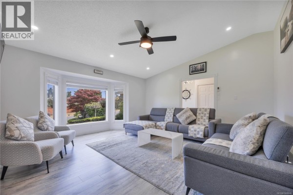 Bright entryway with white tiled floors, a decorative chandelier, and a glass-paned front door. - 6279 Blueback Rd, Nanaimo