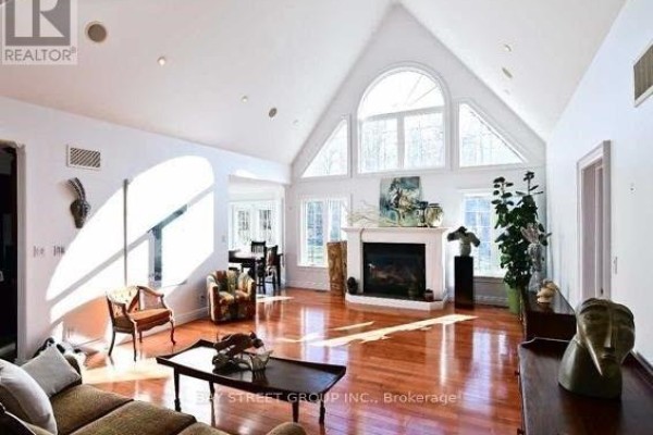 Living room featuring a fireplace, vaulted ceiling with arched windows, and hardwood floors. - 6289 Black River Road, Georgina