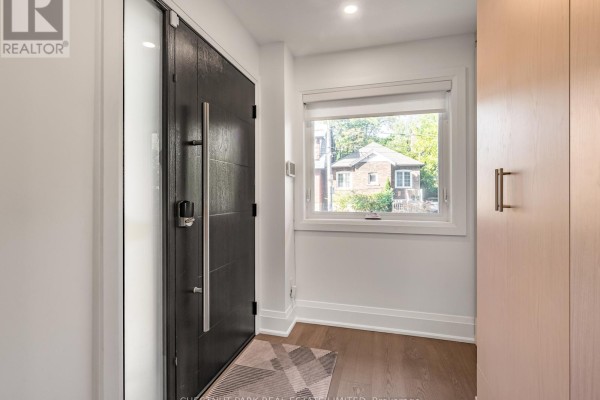 Modern entryway with black textured door, wood floor, and closet. - 629 Duplex Avenue, Toronto
