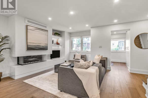 Living room with grey sectional sofa, modern fireplace, and wood floors. - 629 Duplex Avenue, Toronto