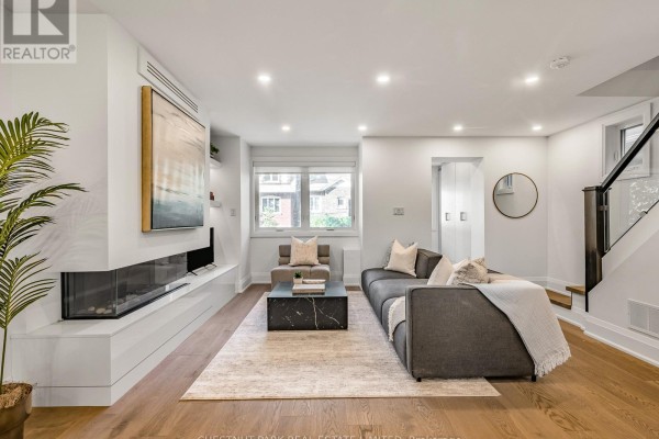 Living room with fireplace, sectional sofa, coffee table, and stairs. - 629 Duplex Avenue, Toronto
