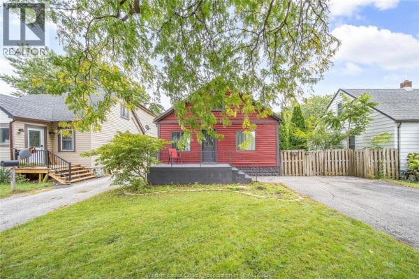 Front exterior of a red clad bungalow with a covered porch and a grass lawn. - 629 Stanley Street, Windsor