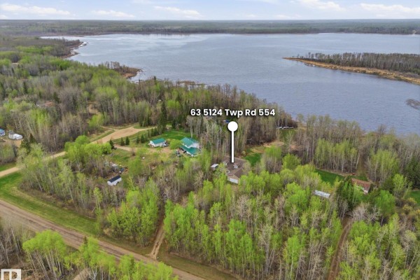 Aerial view showing the property's location amidst trees and near a large body of water. - 63 5124 Twp Road 554, Rural Lac Ste  Anne County