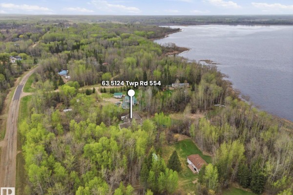 Aerial view of the property showing it is situated among dense trees near a lake. - 63 5124 Twp Road 554, Rural Lac Ste  Anne County