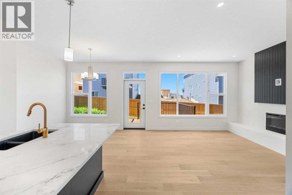 Open concept living area with a kitchen island, large windows, and a gas fireplace. - 63 Annette Rise Nw, Calgary
