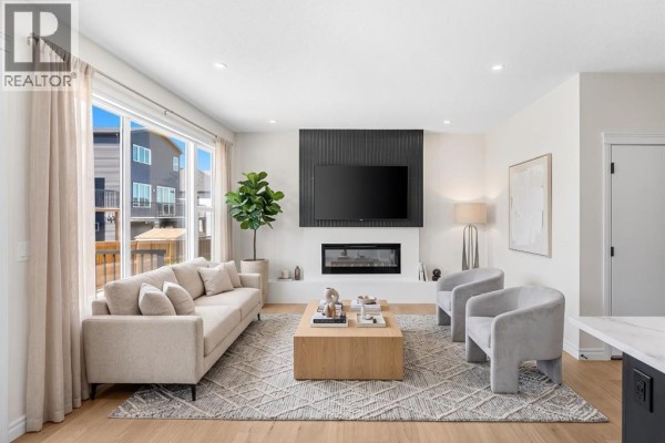 Living room featuring a modern sofa, two armchairs, and a wood coffee table in front of a fireplace. - 63 Annette Rise Nw, Calgary