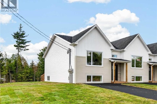 Side view of a townhouse with white and beige siding, asphalt driveway, and trees. - 63 Ardoise Street, Moncton