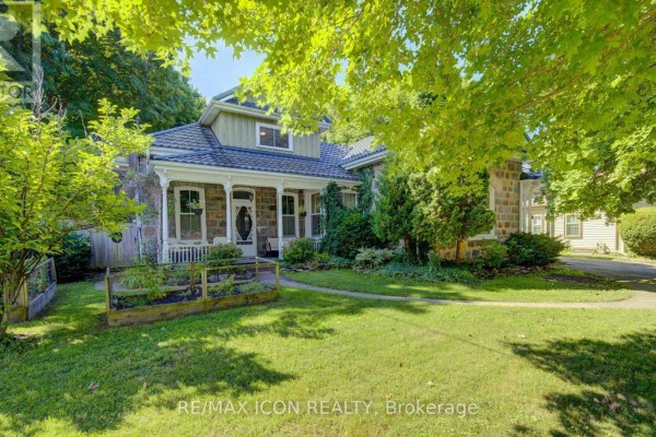 Side view of the stone house showing a welcoming porch with seating and lush landscaping. - 63 Birch Street, Cambridge