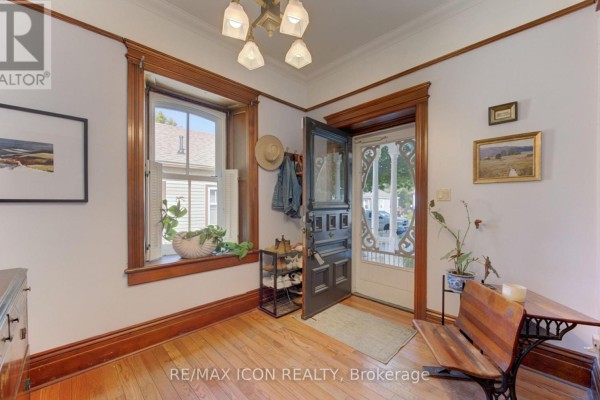 Hallway with hardwood floors, wooden doors, a dresser, and an arched mirror above. - 63 Birch Street, Cambridge