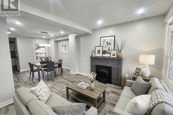 Living room with grey couches, dark wood coffee table, and grey brick fireplace. - 63 Gage Avenue N, Hamilton