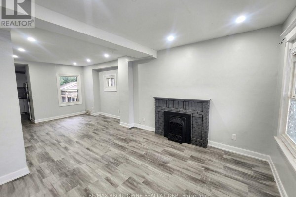 Living room with grey floors, fireplace, and large windows. - 63 Gage Avenue N, Hamilton