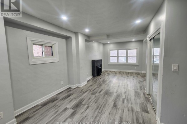 Living room with grey walls, fireplace, and windows facing the street. - 63 Gage Avenue N, Hamilton