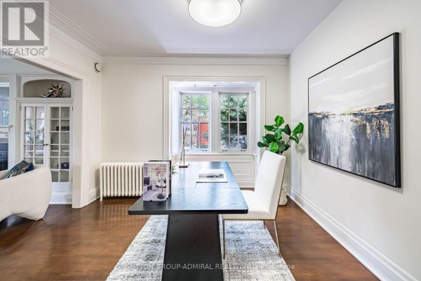 Home office with desk, chair, rug, and view into a wood-paneled staircase. - 63 Highland Avenue, Toronto