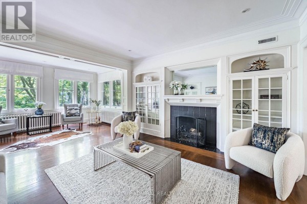 Living room with fireplace, white sofas, long coffee table, and glass-paneled doors. - 63 Highland Avenue, Toronto