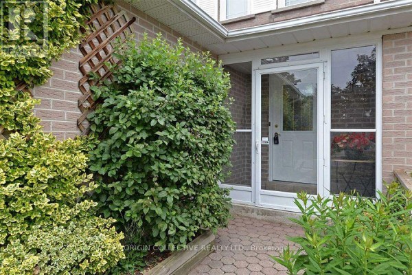 Close-up of the front door entrance with green bushes and a paved walkway. - 63 Humphrey Drive, Ajax