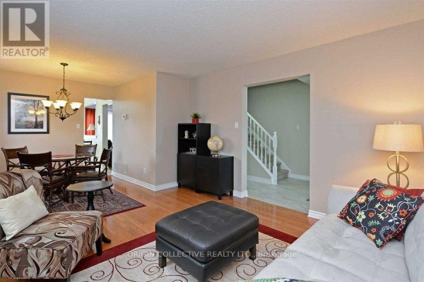 Living room with hardwood floors, beige walls, and view into the dining area and staircase. - 63 Humphrey Drive, Ajax