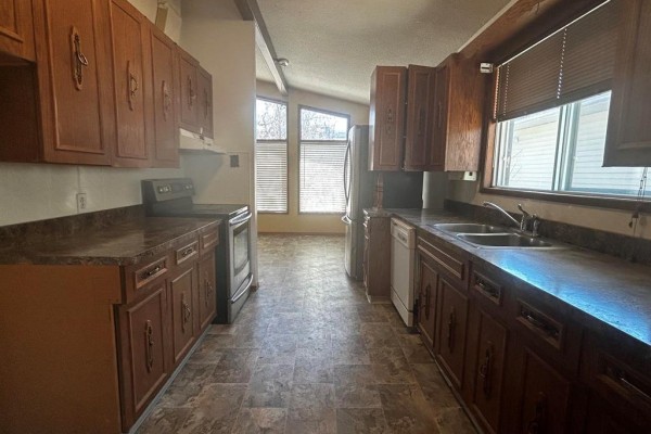 Kitchen with dark wood cabinets, laminate countertops, and stainless steel appliances. - 63 Main Street, Riverton