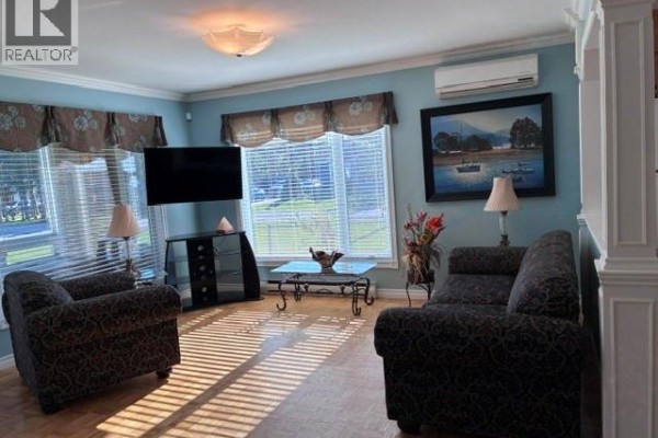 Living room with blue walls, two sofas, two chairs, a television, and blinds. - 63 Parise Street, Caraquet