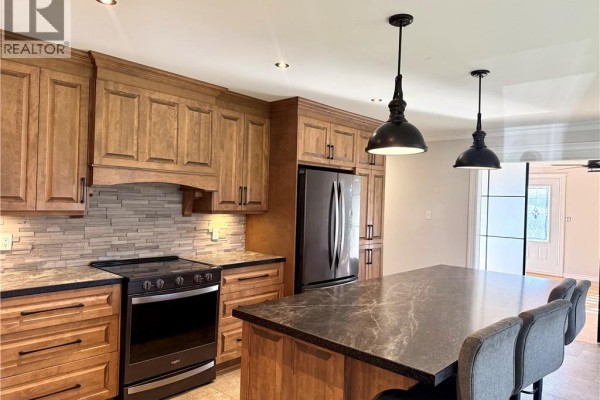 Grey bathroom with a white vessel sink, black faucet, and a wooden vanity. - 63 Premiere Avenue, Sainte Anne De Madawaska