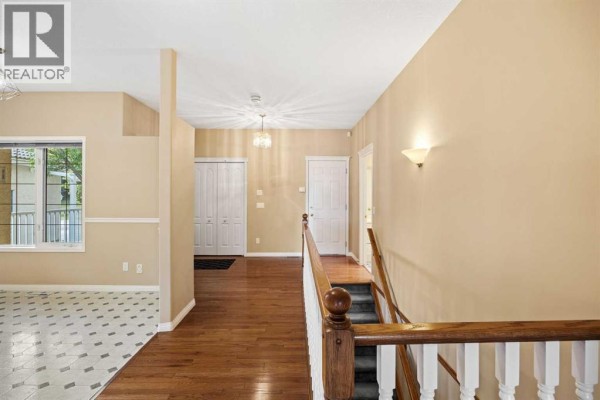 Hallway overlooking a staircase with white spindles and a wood handrail, leading to bedrooms. - 63 Scimitar Heath Nw, Calgary