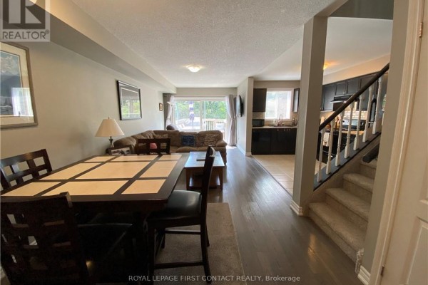 Dining area with dark wood table, leading to living room and kitchen. - 63 Sydenham, Barrie