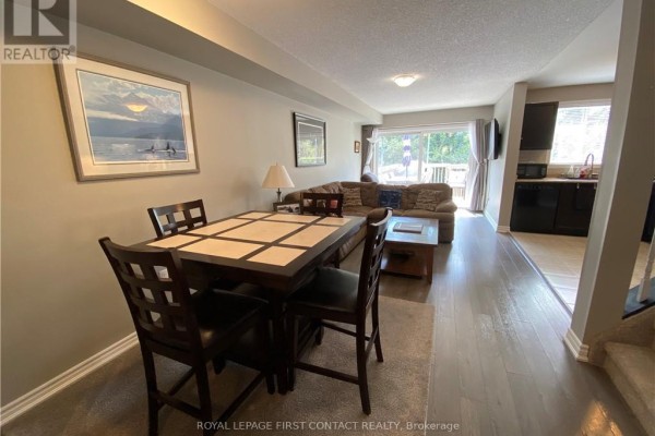 Dining area with dark wood table and chairs, overlooking living room and deck. - 63 Sydenham, Barrie