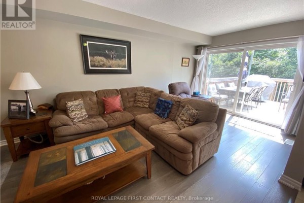 Living room with large brown sectional sofa, coffee table, and access to deck. - 63 Sydenham, Barrie