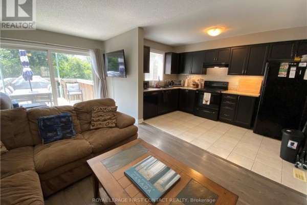 Living room adjacent to a modern black kitchen with tile flooring. - 63 Sydenham, Barrie