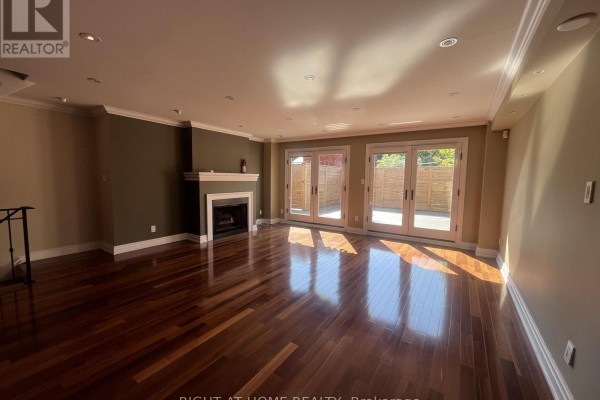 Living room fireplace with white mantel, hardwood floors, and double glass doors. - 63 Walker Avenue, Toronto