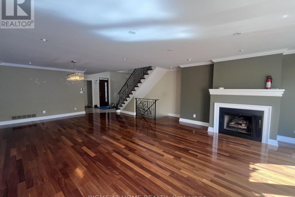 Open-concept living space with hardwood floors, neutral walls, and staircase. - 63 Walker Avenue, Toronto