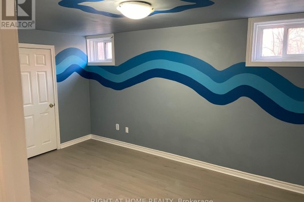 Room with grey walls and blue wave mural, featuring two windows and wood laminate flooring. - 630 Cartier Avenue, Oshawa