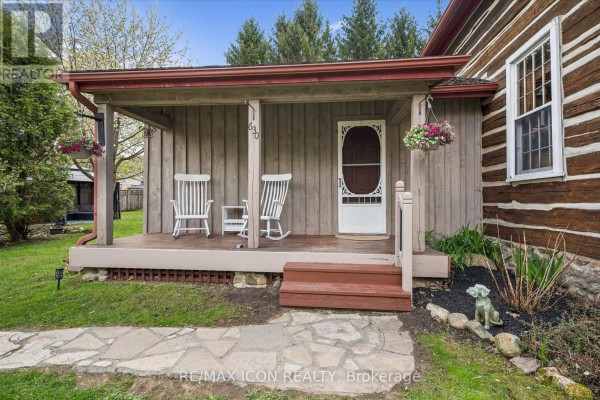 Close-up of the covered front porch with two rocking chairs and hanging flower baskets. - 630 Robert Ferrie Drive, Kitchener
